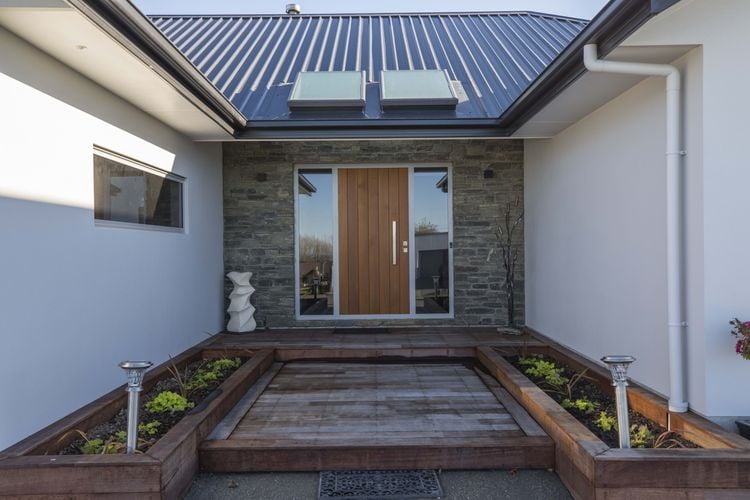 Front entryway to home with timber decking and stairs and large wooden door