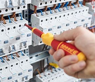 using an adjustable red and yellow wiha screwdriver to adjust a circuit breaker