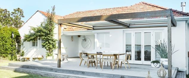 House with timber decking entertaining area with dining table and chairs