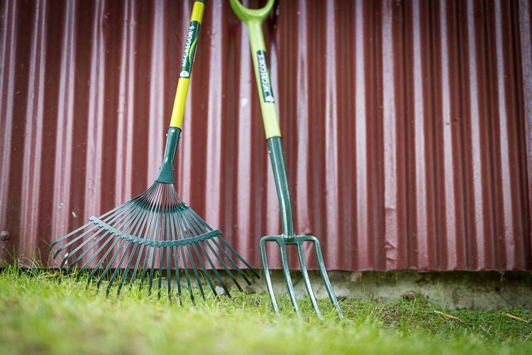 Rake and garden fork sitting against a wall