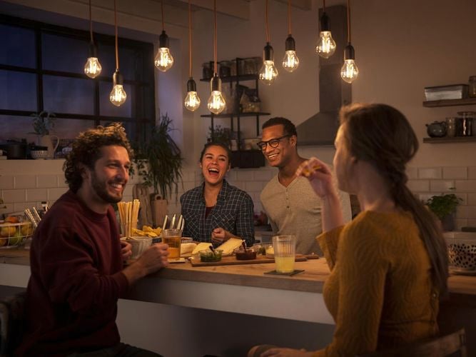 Four people sitting around the kitchen bench laughing