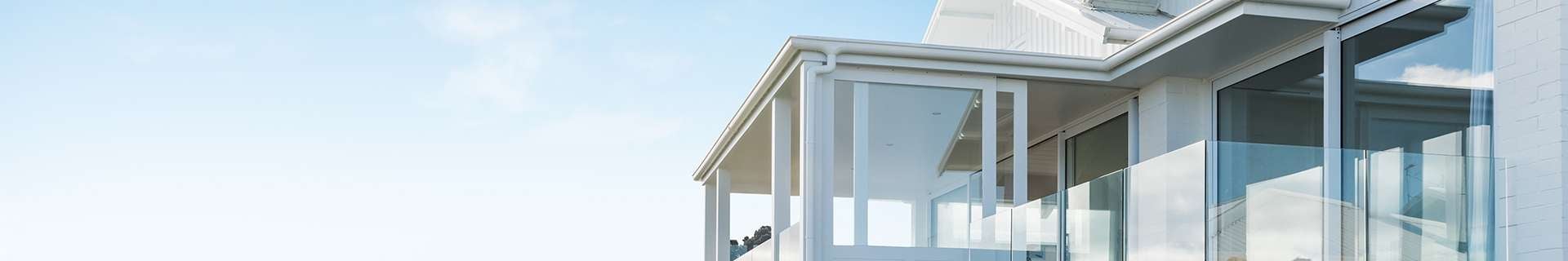 White weatherboard house with glass balcony.