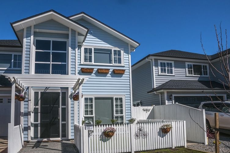 Front of two-story blue home with white fence