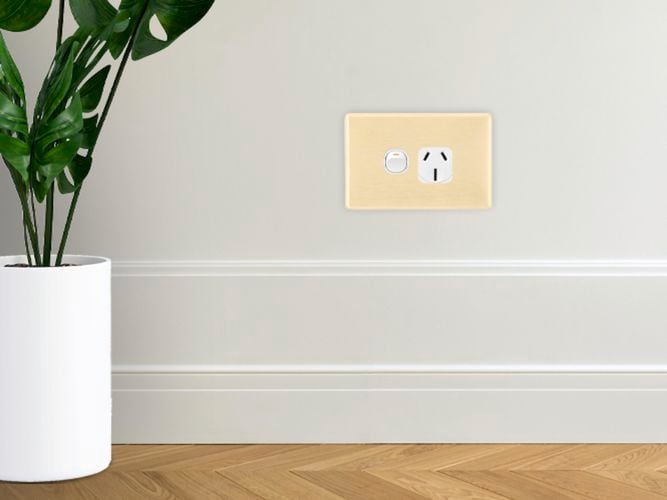 Brushed gold single gang grid plate on a pale white wall.