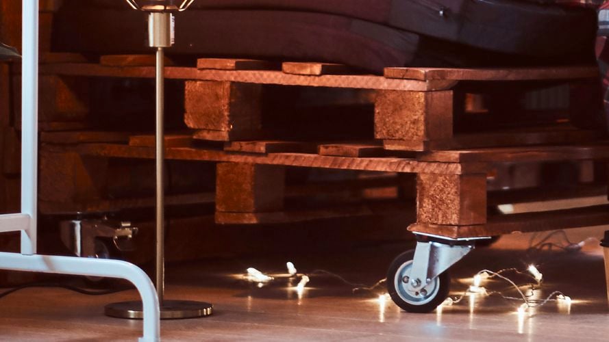 Sofa pallet stack with wheels and lamp.