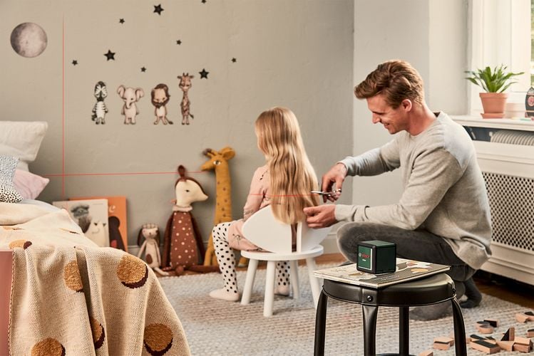 Man using laser level to cut daughter's hair