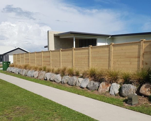 Tall laminated timber fence between house and pedestrian path