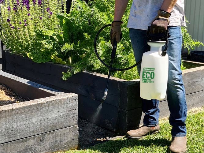 Eco sprayer being used on bottom of garden bed