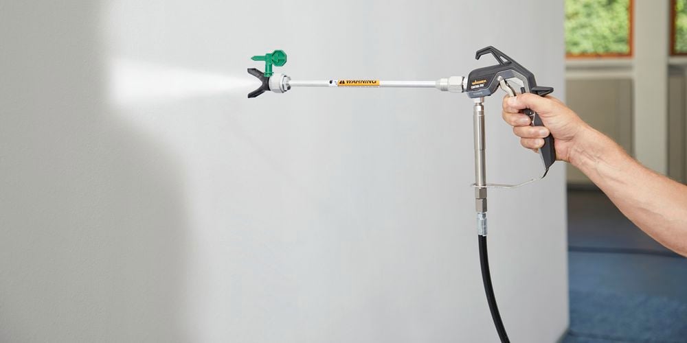 Wagner
  Control Pro Hybrid Gun attached to 30cm extension with Control Pro Tip 311 to
  spray a wall with off-white paint