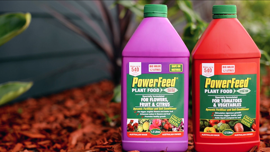 Two bottles of fertiliser sitting on garden bed