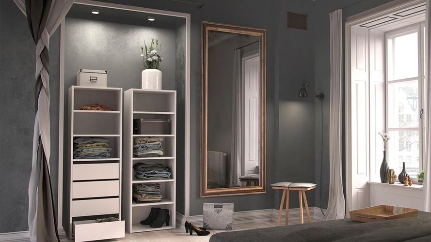 Organized built in wardrobe in room with chair and plant. 