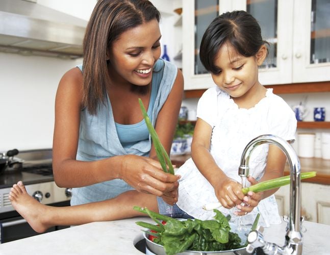 Mother and daughter washing vegetables in the sink