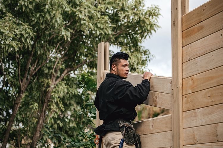 Person installing timber fence panel 