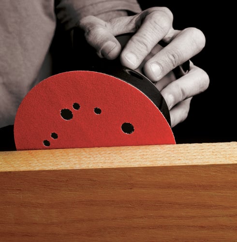 Person using powered circular sander to sand timber
