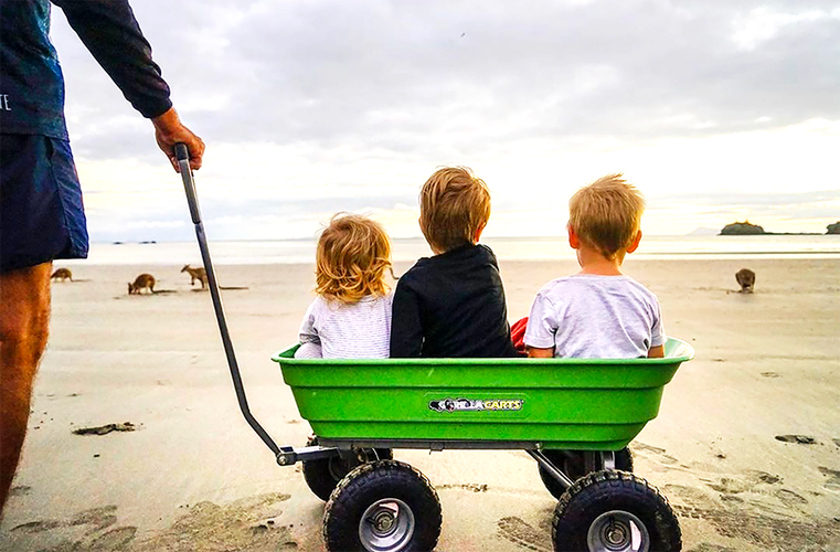 Three kids sitting on cart at the beach