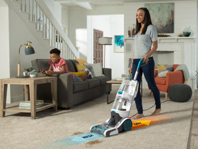 A woman cleans a carpet using a Smartwash carpet washer, moving forward to wash and backwards to dry with Hoovers Smartwash technology.