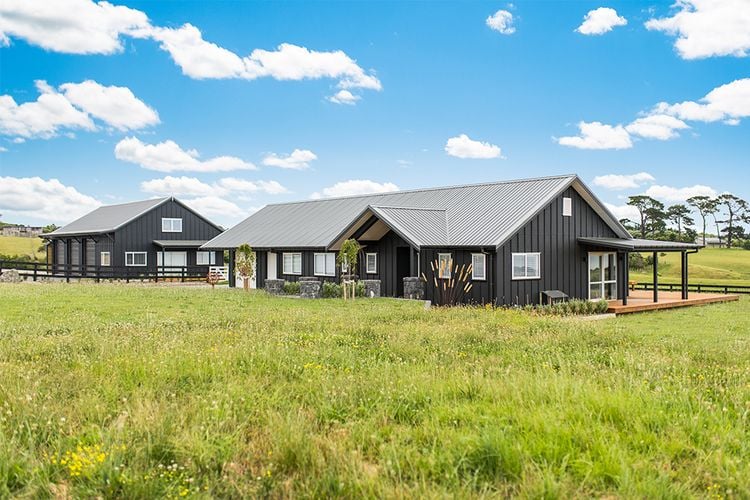 Farm house exterior with tall grass, timber decking and barn