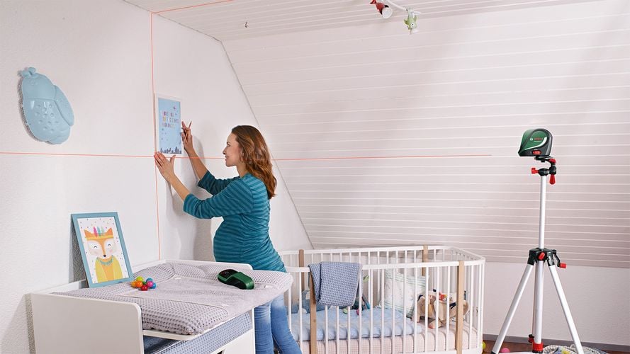 Woman using laser level to help hang pictures on wall
