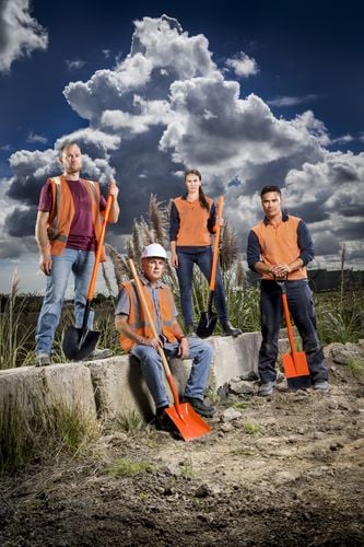 Four individuals standing with digging tools
