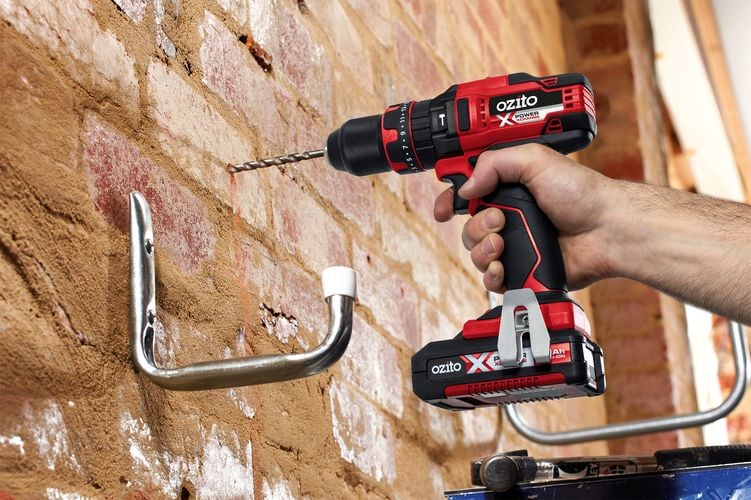Person drilling hole into brick wall