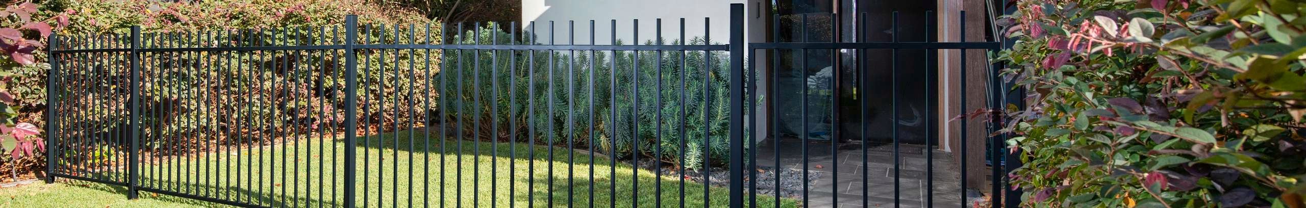 Black flat top fencing at the front of a modern house.