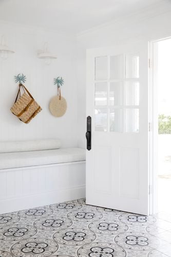 Entry to home with opened white wooden door and patterned tiles