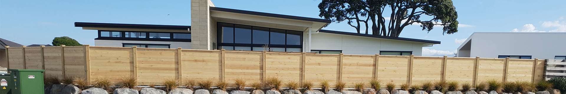 Timber fence with rocks and plants in front of it.