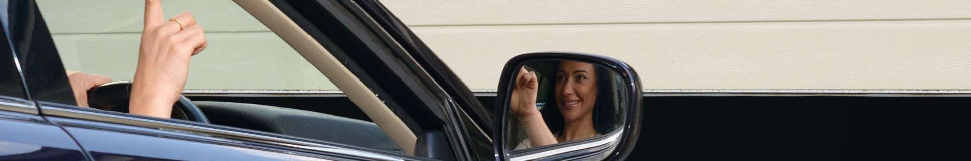 Woman in car using remote to open garage door
