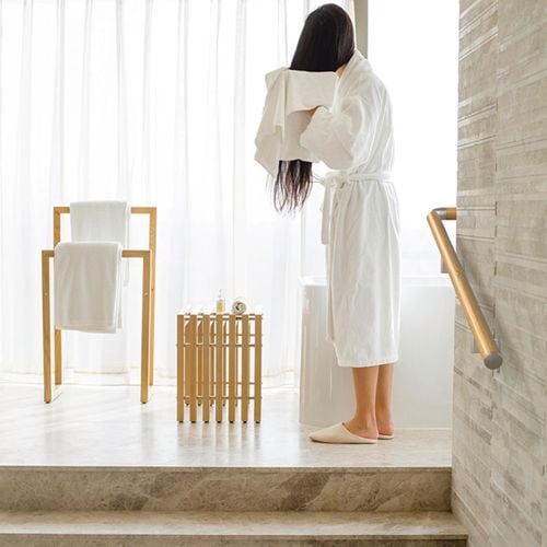 A lady drying her hair with a towel in a modern tiled bathroom with scandi decor