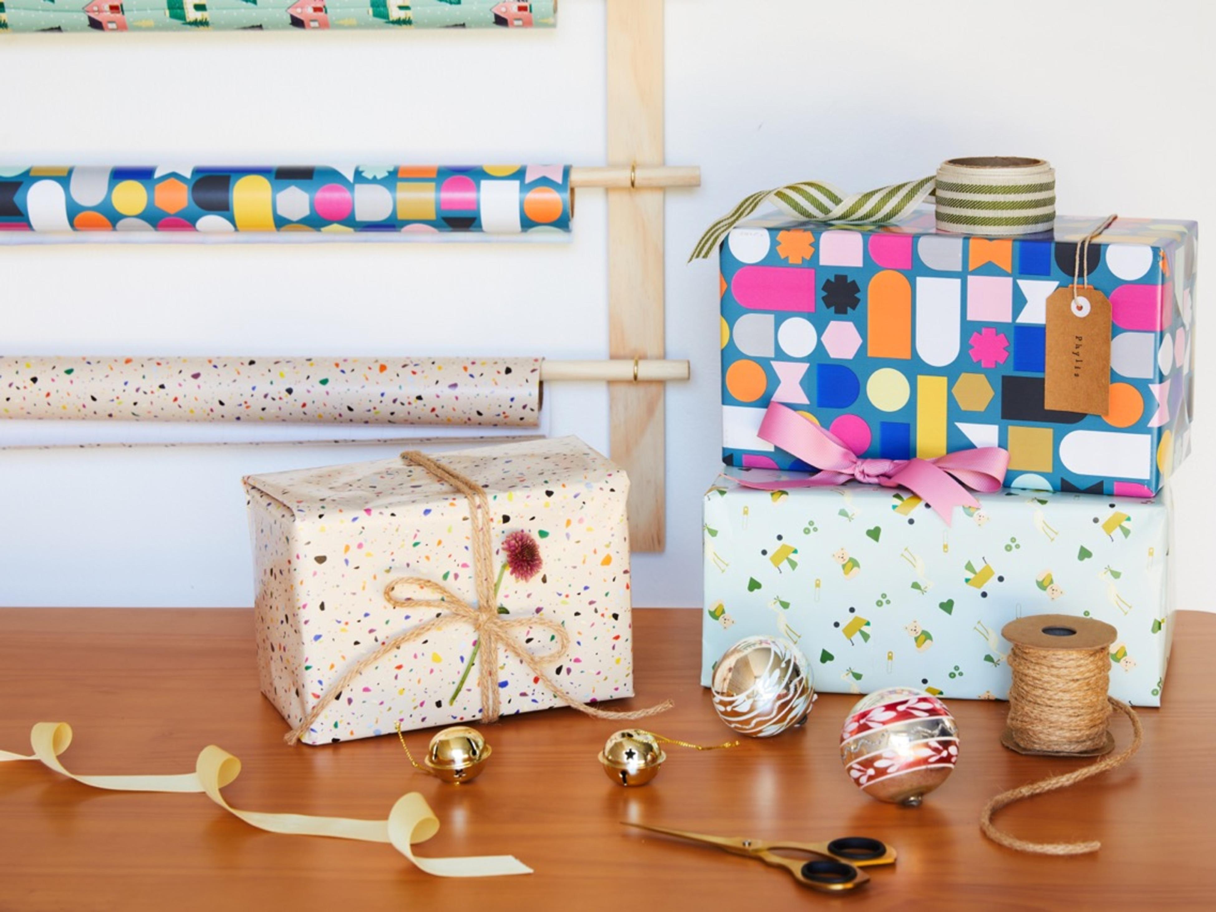 Roll Of Wrapping Paper Scissors Gift Bow And Box On Wooden Table