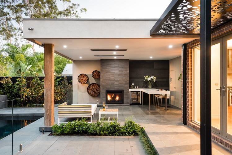 Covered outdoor entertaining area with heaters attached to ceiling and fireplace