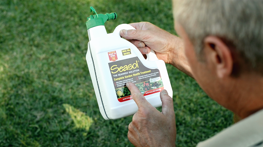Man holding bottle of fertiliser and pointing at label