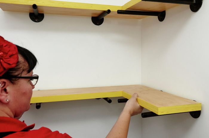 A completed shelf being placed on mounted wall pegs