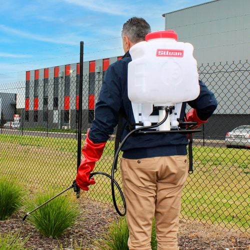 Backpack sprayer being used on garden bed
