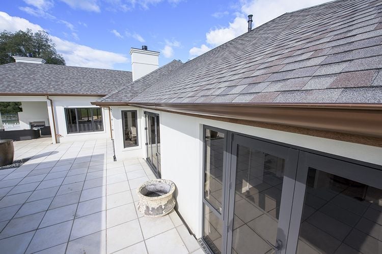 House exterior with tiles and copper-coloured PVC gutters and drainage pipe