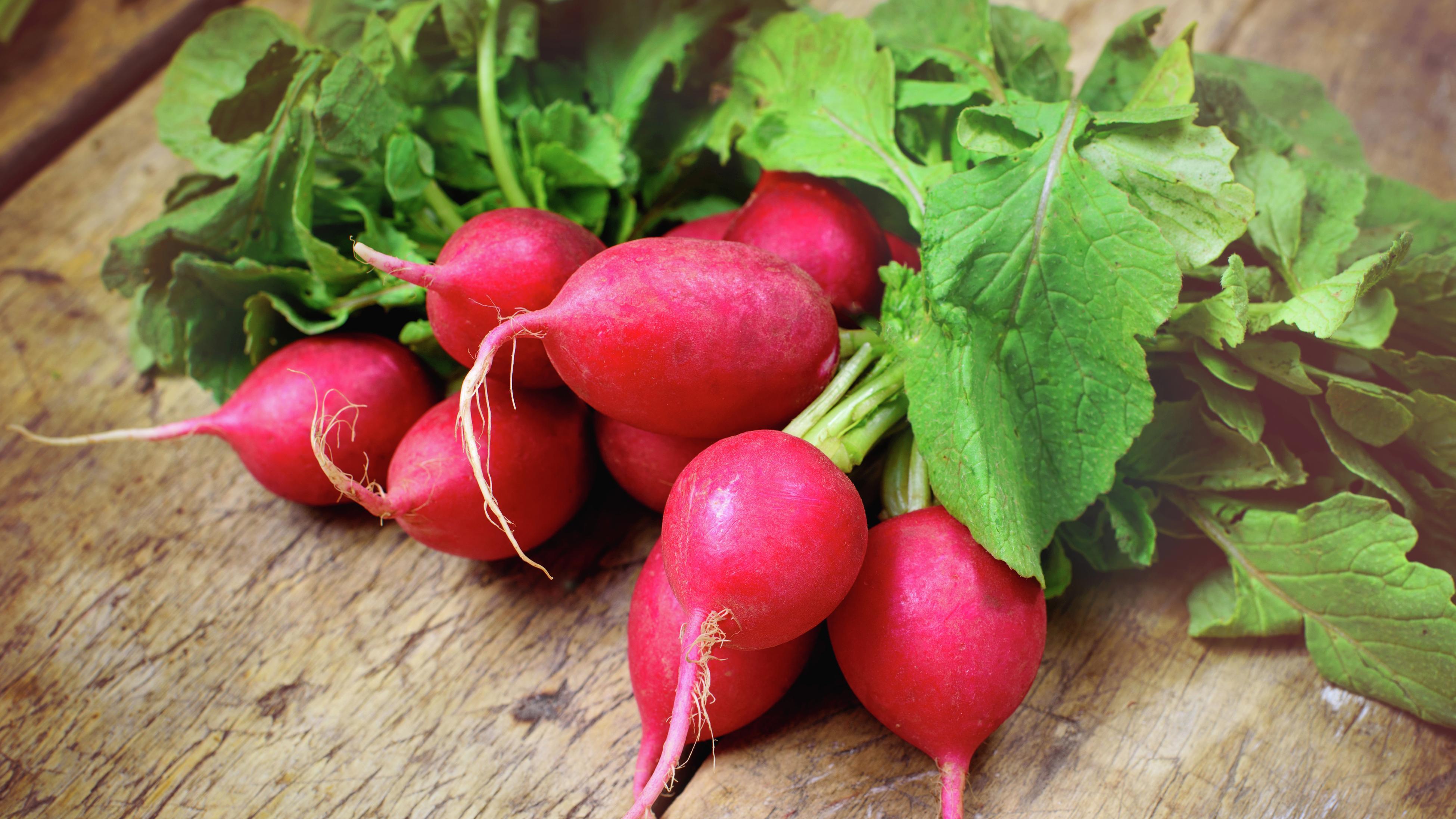 A bunch of red radishes on a wooden table