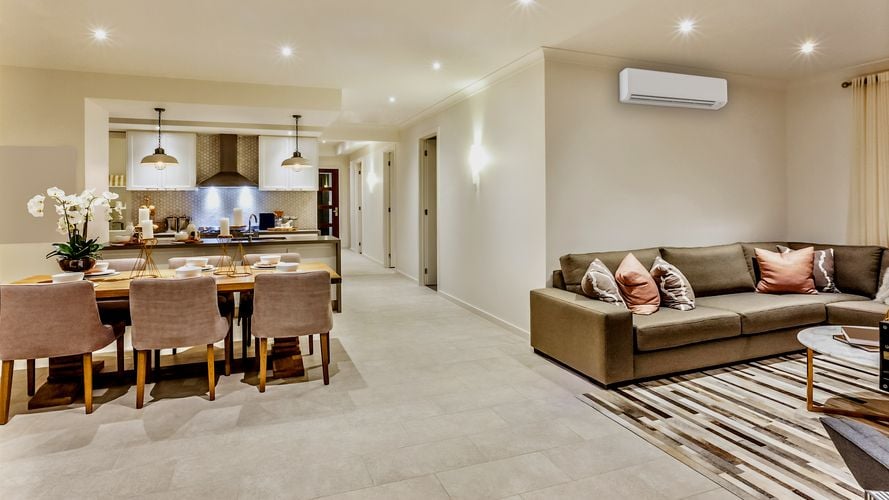 Lounge room with brown L-shaped couch underneath an air conditioning unit