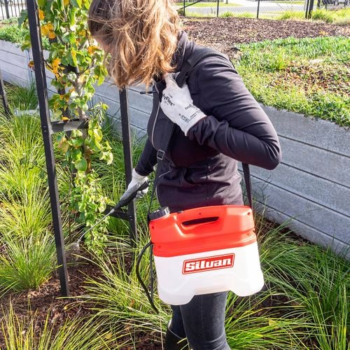 Handheld sprayer being used in a garden bed