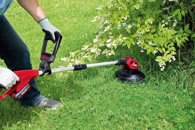 Person using trimmer to cut grass