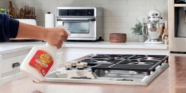 Person spraying Krud Kutter Cleaner and Degreaser onto kitchen stove