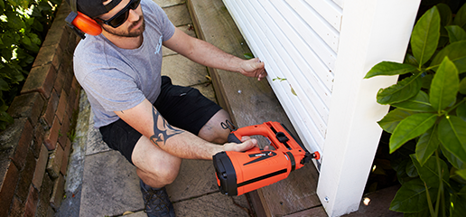 Person nailing timber to post using nail gun