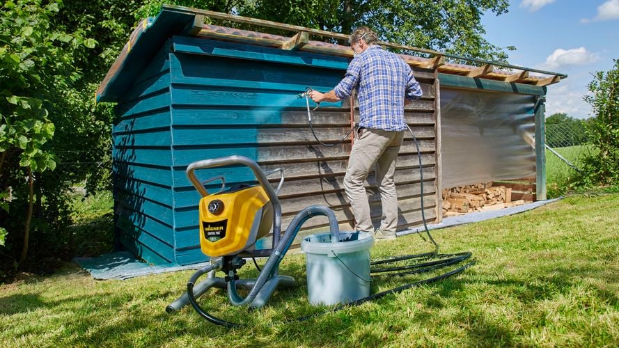 Wagner
  Control Pro 250M spraying teal paint to a wooden shed to rejouvinate it
