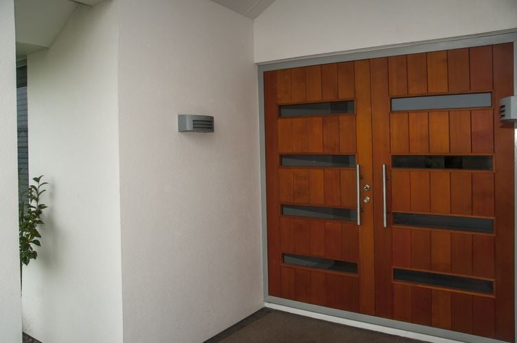 Large wooden double door in front entryway with steel handle