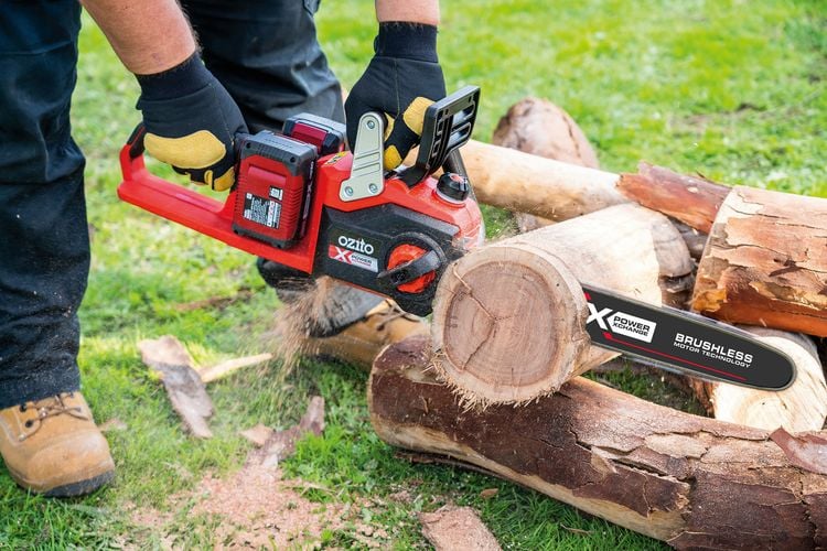 Person using battery-powered chainsaw to cut log