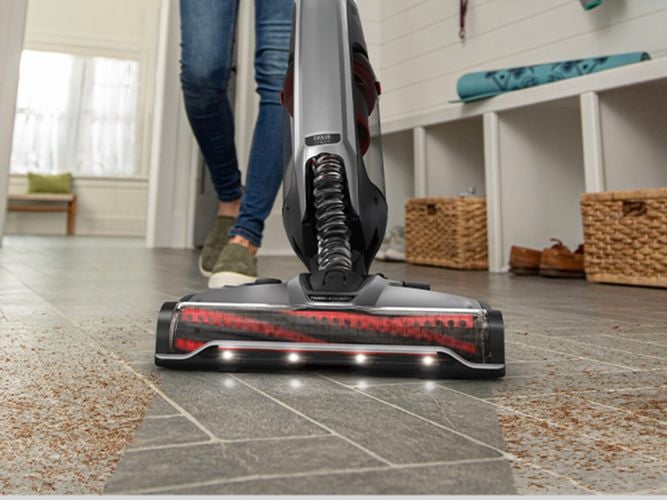 A woman efficiently cleans the floor using a Hoover Evolve cordless vacuum cleaner, ensuring a spotless and dust-free environment.