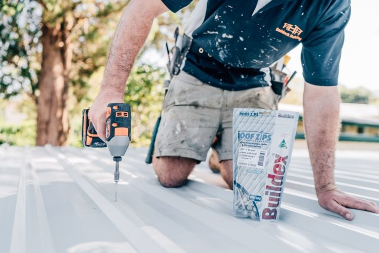 Man drilling screw into corrugated roof