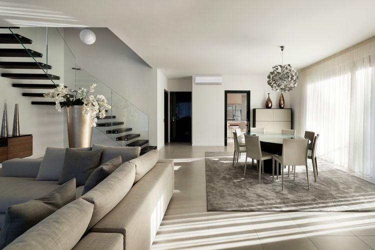 Lounge and dining room with grey couch. glass-topped dining table and grey carpet