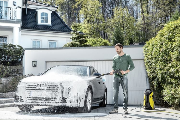 Person using high pressure hose to clean car