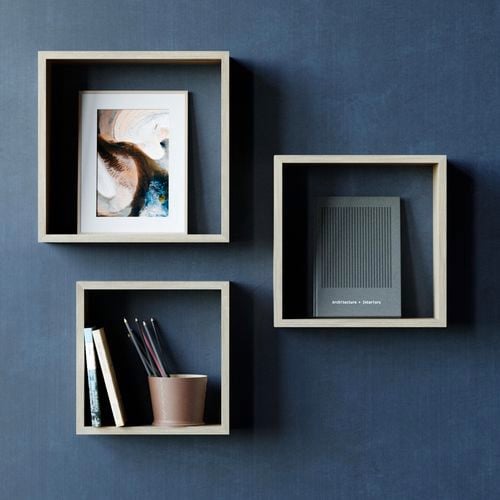 Three square wall shelves on a dark blue wall.
