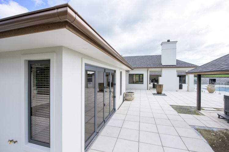 House exterior with tiles, pool and copper-coloured PVC gutters and drainage pipe